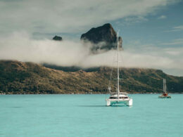 View of Bora Bora from the sea, with a catamaran in the foreground.