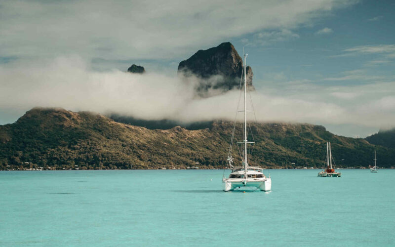 View of Bora Bora from the sea, with a catamaran in the foreground.