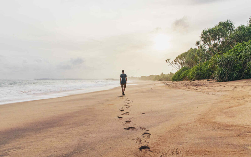 Man walking along the beach in Tangalle, Sri Lanka.